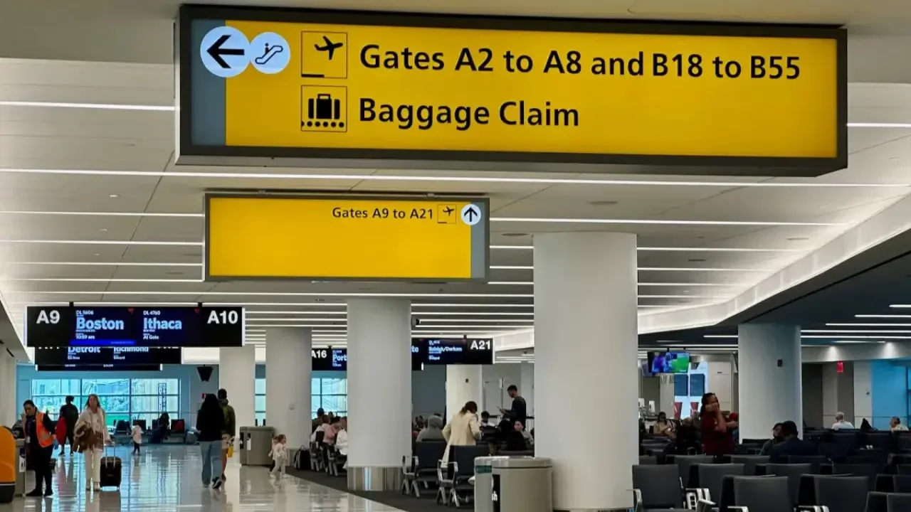 People collecting luggage at JFK Airport baggage claim area